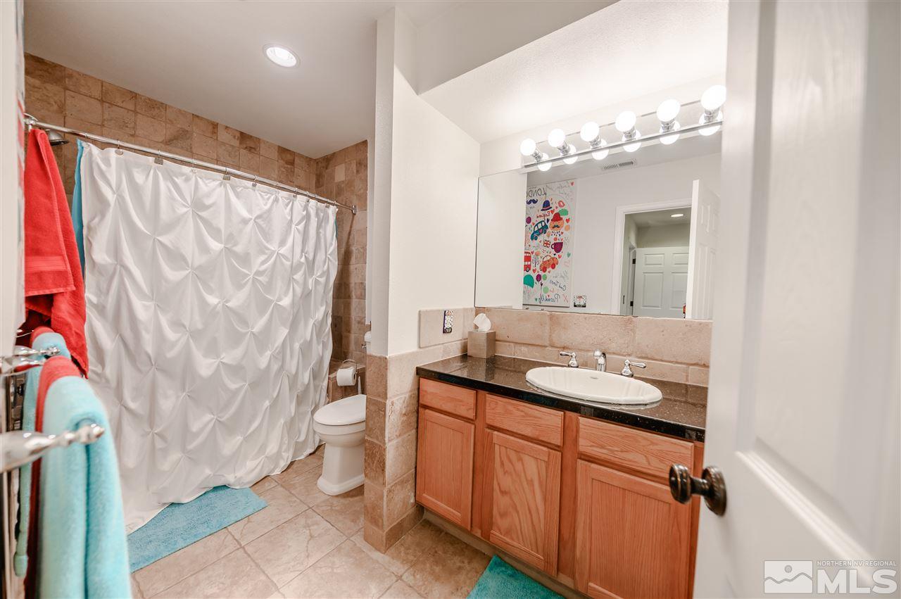 10300 Silva Ranch Road Reno, NV 89523 - Photo 14 of 25 a bathroom with a granite countertop sink a toilet and a mirror