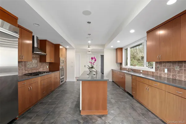 a large kitchen with stainless steel appliances kitchen island granite countertop a large counter top and a stove