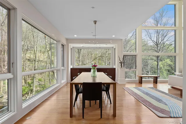 a dining room with wooden floor a chandelier a flat screen tv and windows