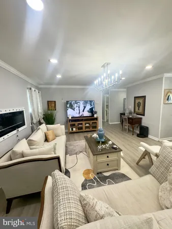 a living room with furniture a chandelier and a flat screen tv