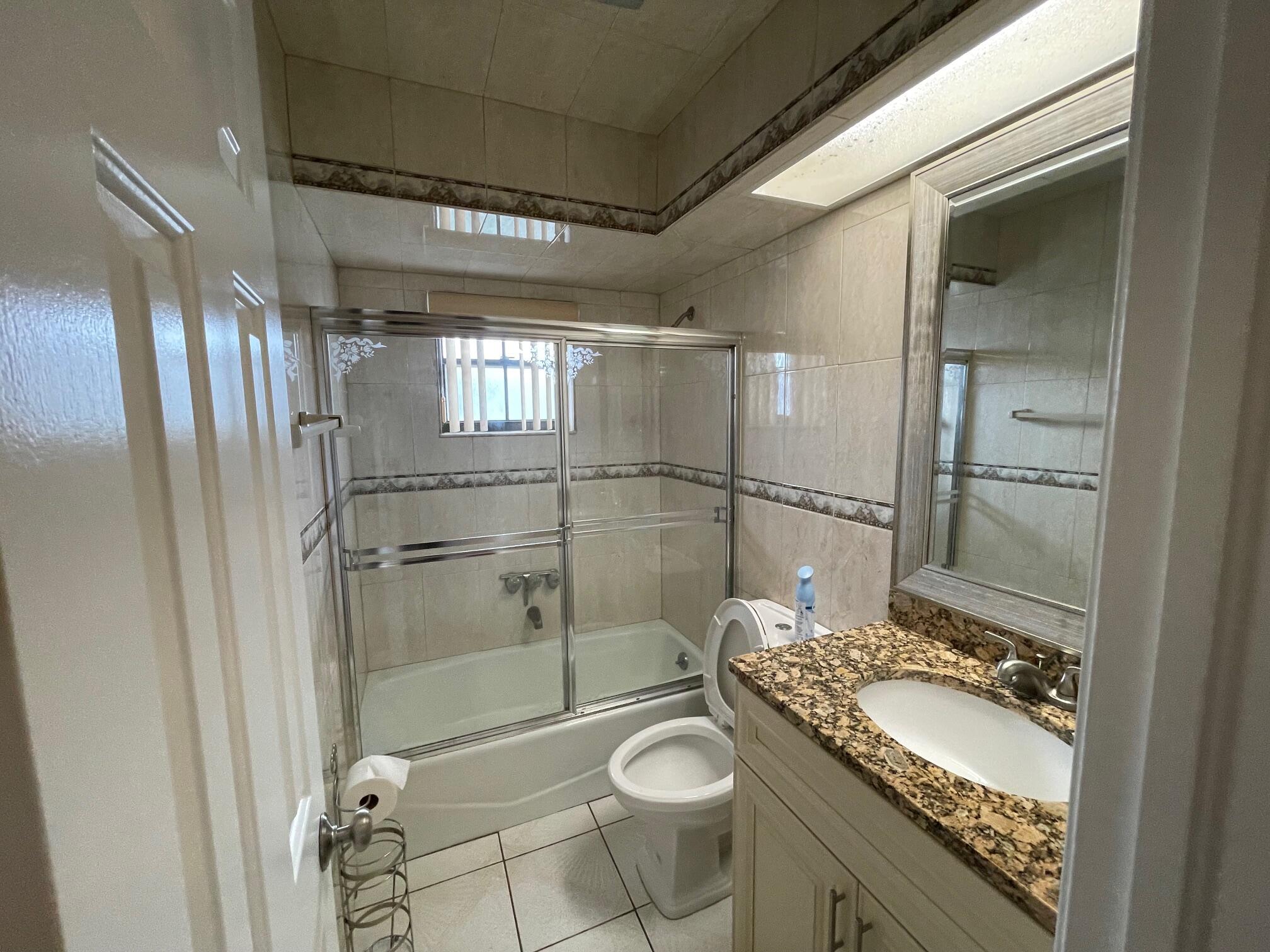 2601 West Carandis Road West Palm Beach, FL 33406 - Photo 9 of 13 a bathroom with a granite countertop sink toilet and shower