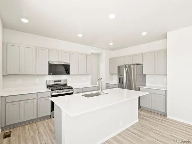 a kitchen with stainless steel appliances a sink a stove a refrigerator and cabinets