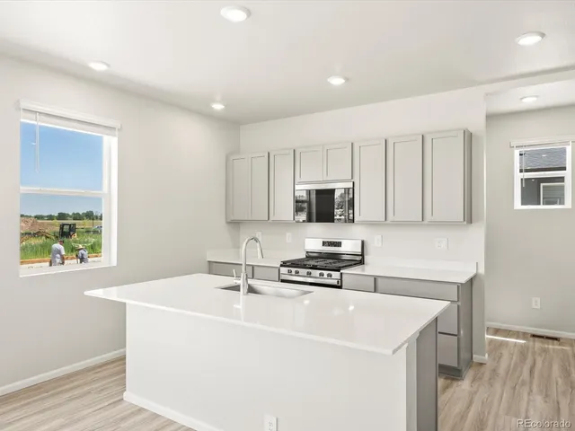 a kitchen with stainless steel appliances a sink a stove a microwave a sink a refrigerator and cabinets