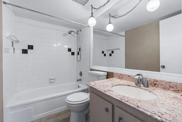 a bathroom with a granite countertop sink a toilet and shower