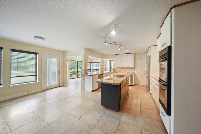 a large white kitchen with a sink and dishwasher a refrigerator with white cabinets