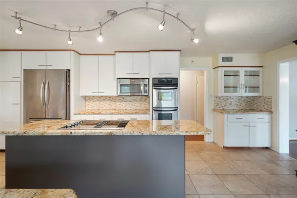 a kitchen with kitchen island granite countertop a stove a sink and a refrigerator