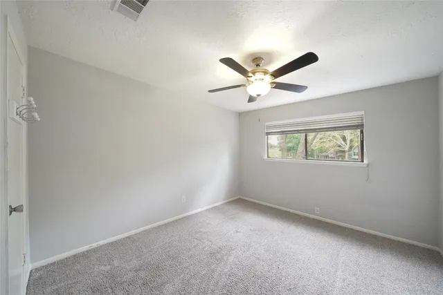 an empty room with a window and a ceiling fan
