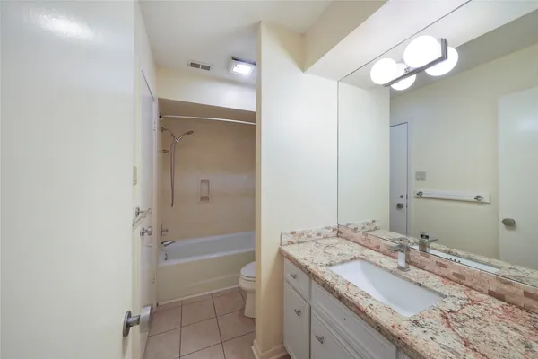 a bathroom with a granite countertop sink a mirror and a bathtub