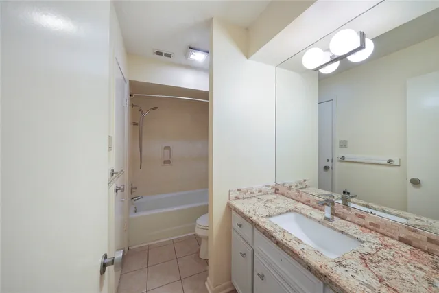 a bathroom with a granite countertop sink a mirror and a bathtub