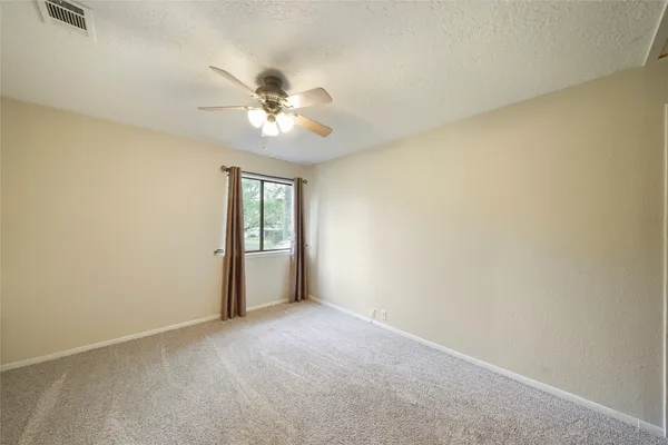 an empty room with windows and fan
