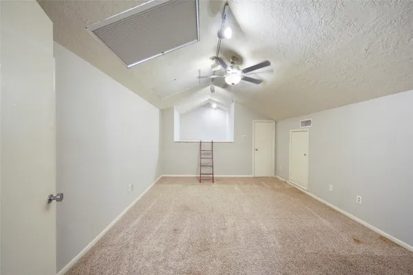 a view of an empty room with a chandelier fan and a window
