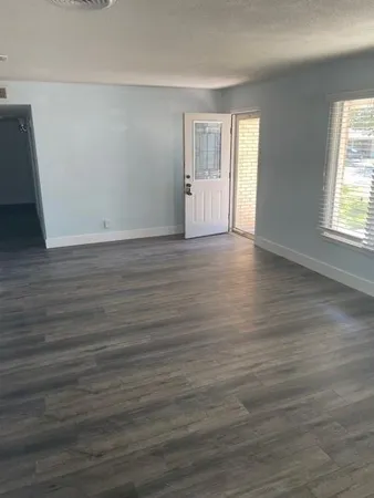 a view of an empty room with wooden floor and window