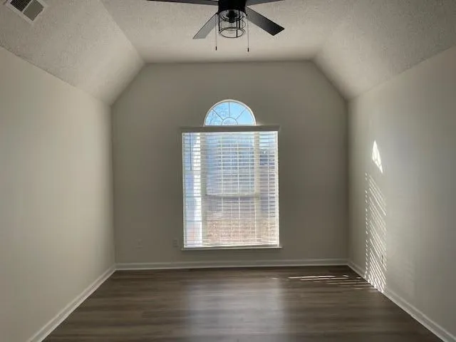 an empty room with a chandelier fan and windows