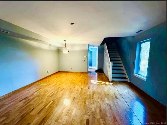 a view of an empty room with wooden floor and stairs