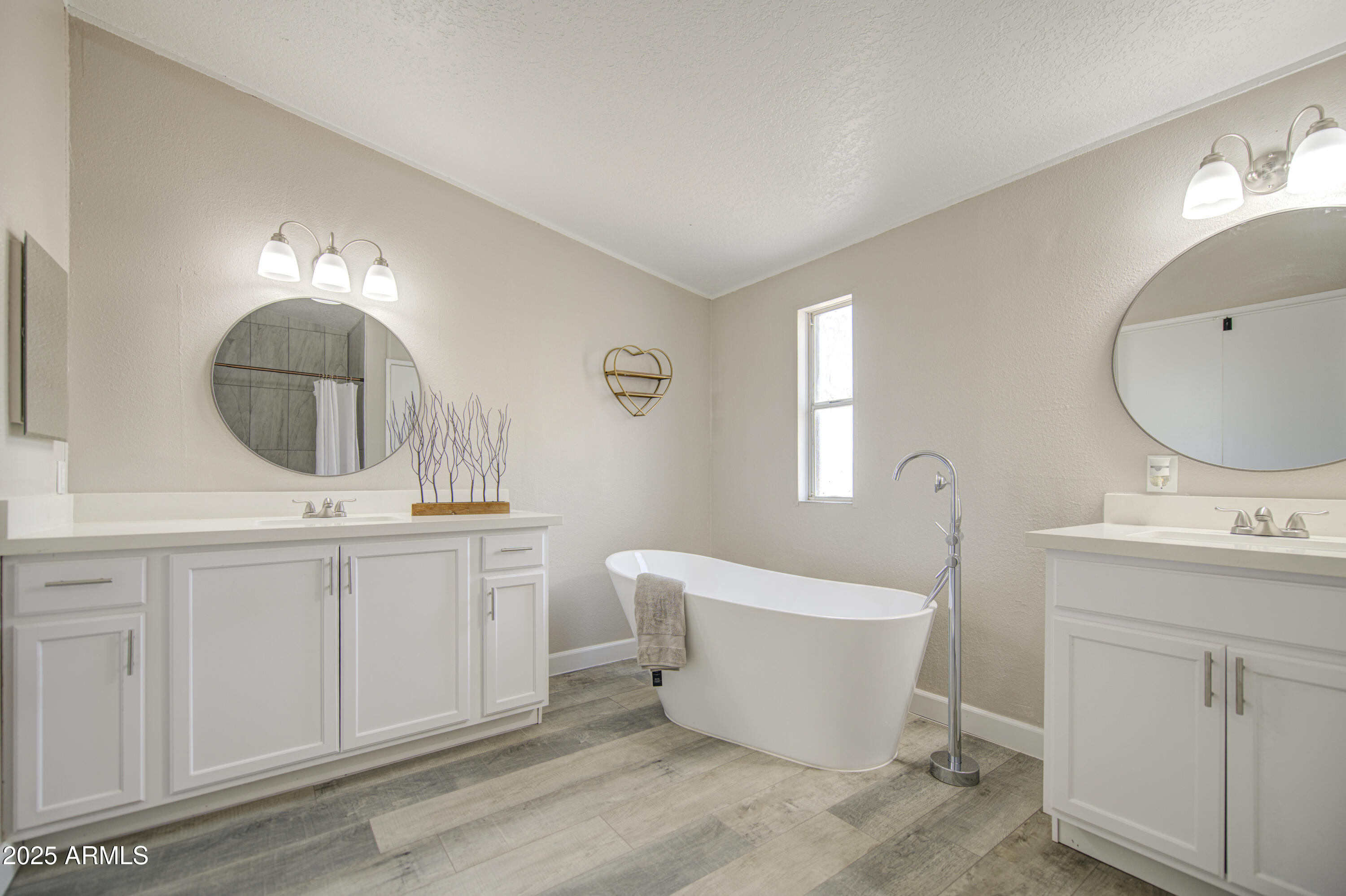 19954 West Teepee Road Buckeye, AZ 85326 - Photo 32 of 46 a spacious bathroom with a double vanity sink a mirror a bathtub and window