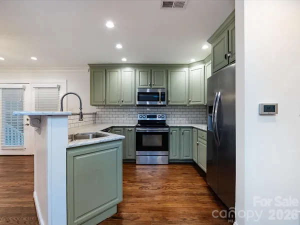 a kitchen with stainless steel appliances granite countertop a refrigerator stove and sink