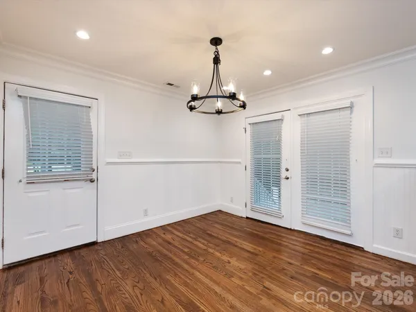 an empty room with wooden floor cabinet and windows