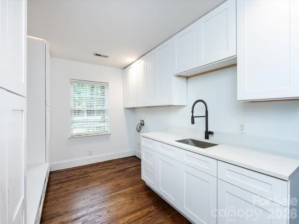 a kitchen with stainless steel appliances granite countertop a sink a window and wooden floor