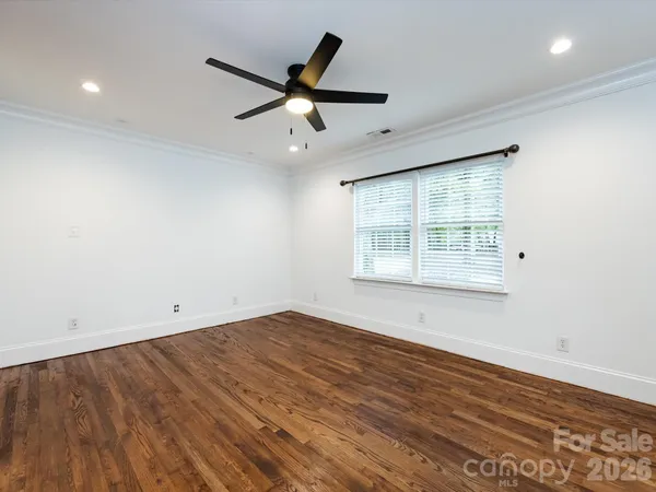 an empty room with wooden floor fan and windows