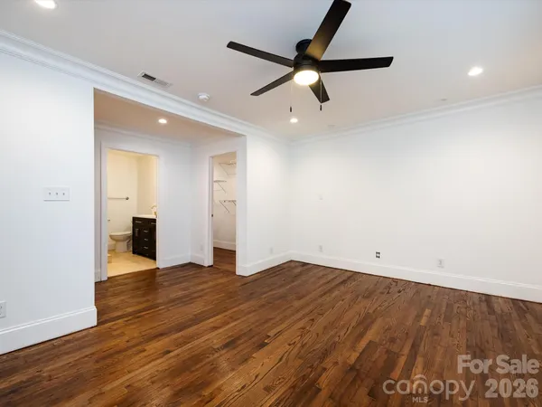 an empty room with wooden floor and a ceiling fan