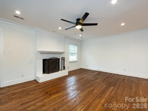 an empty room with wooden floor fireplace and windows