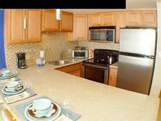 a kitchen with granite countertop a sink a stove and refrigerator