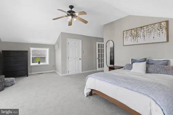 a spacious bedroom with a large bed a chandelier and windows