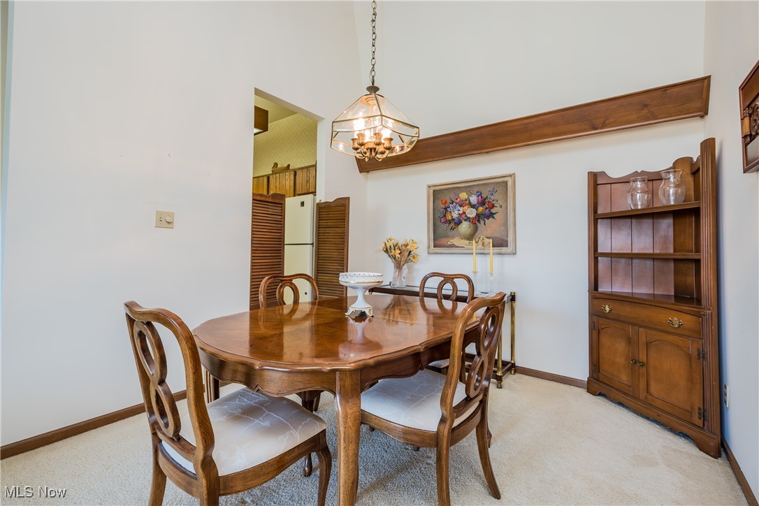 Dining space with light carpet, a notable chandelier, and baseboards