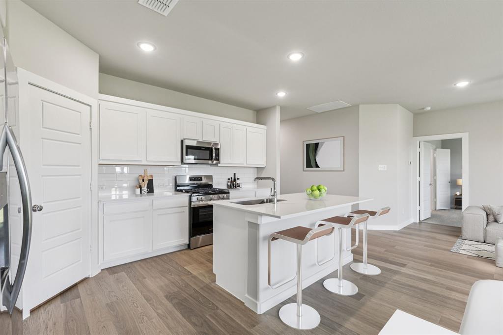 697 Poppy Lane Lavon, TX 75166 - Photo 6 of 27 a kitchen with stainless steel appliances granite countertop a refrigerator a stove top oven a sink dishwasher and white cabinets with wooden floor