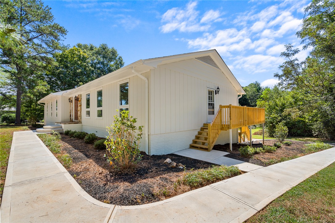 208 Williamsburg Road Anderson, SC 29621 - Photo 4 of 48 A concrete walkway leads past manicured garden beds toward a newly constructed wooden side deck.