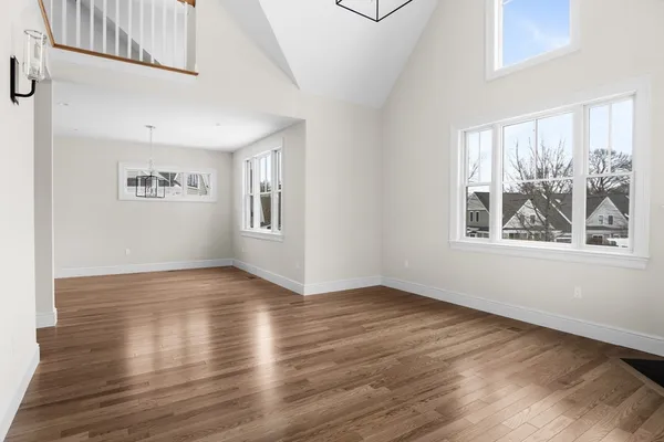 a view of an empty room with window and wooden floor