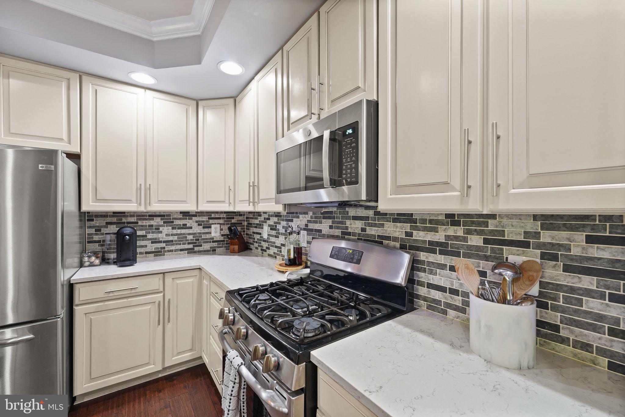 43846 Artsmith Terrace Ashburn, VA 20147 - Photo 12 of 38 a kitchen with white cabinets a sink stove and refrigerator