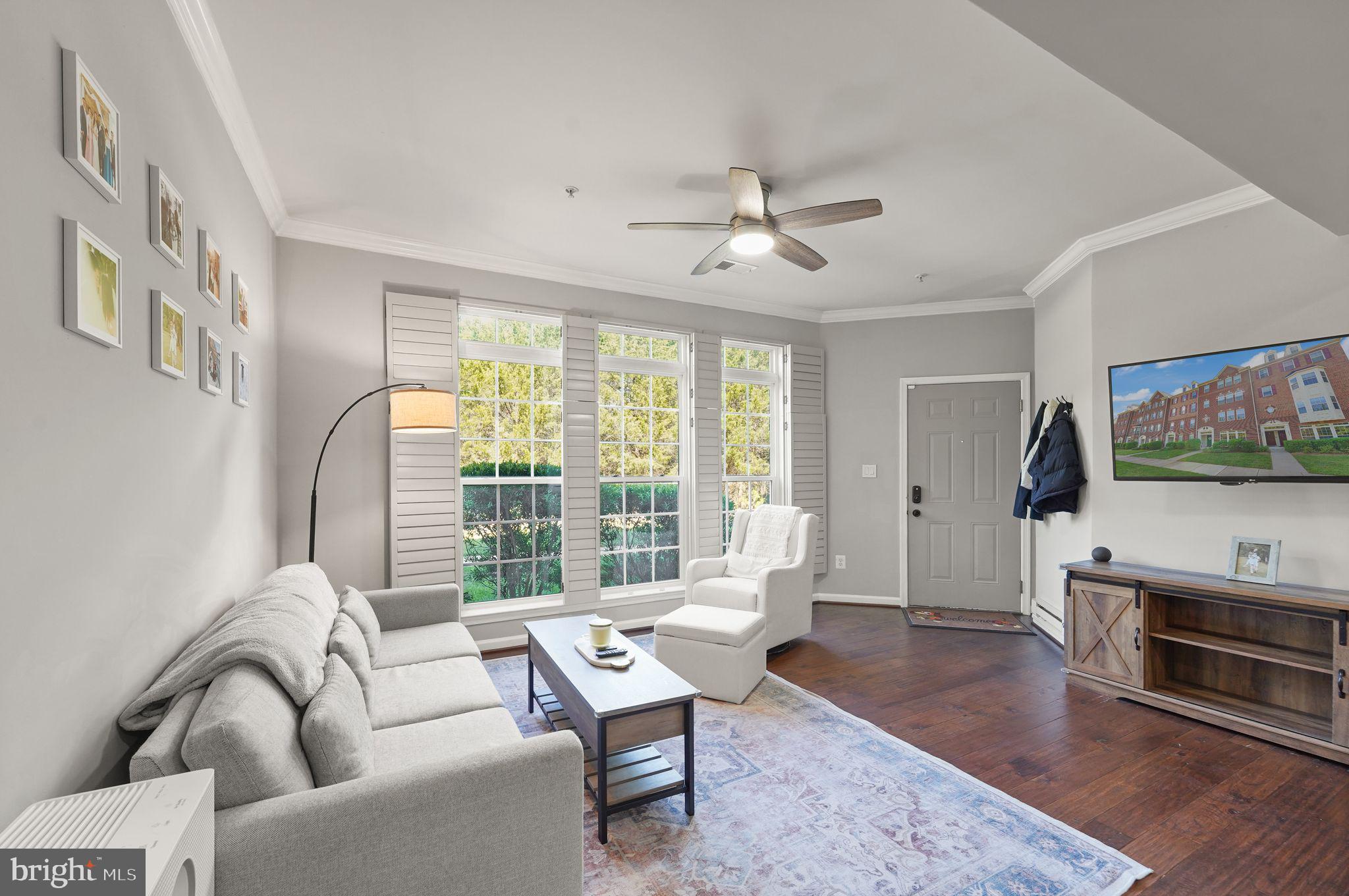 43846 Artsmith Terrace Ashburn, VA 20147 - Photo 5 of 38 a living room with furniture a flat screen tv and a floor to ceiling window
