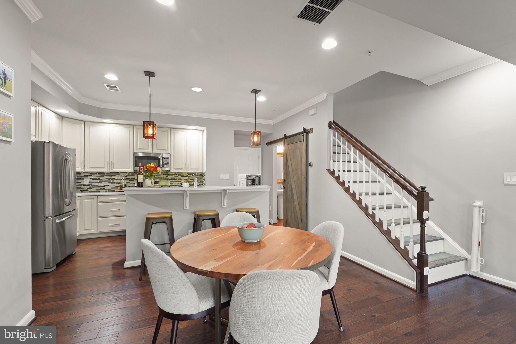 43846 Artsmith Terrace Ashburn, VA 20147 - Photo 7 of 38 a kitchen with white cabinets stainless steel appliances dining table and chairs