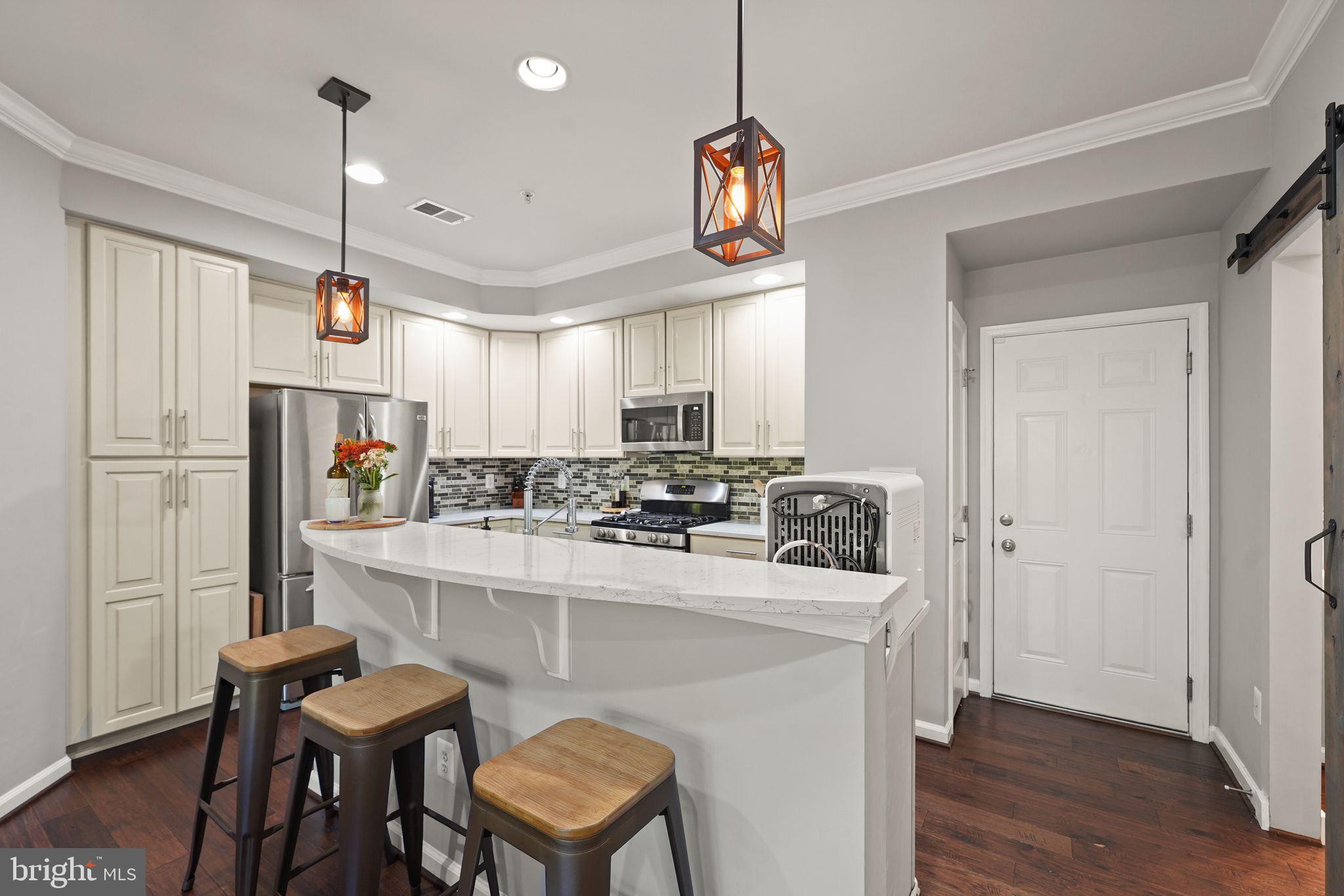 43846 Artsmith Terrace Ashburn, VA 20147 - Photo 10 of 38 a kitchen with kitchen island white cabinets and stainless steel appliances