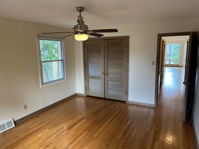 a view of empty room with wooden floor and fan