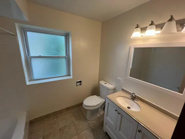 a bathroom with a granite countertop sink toilet and mirror