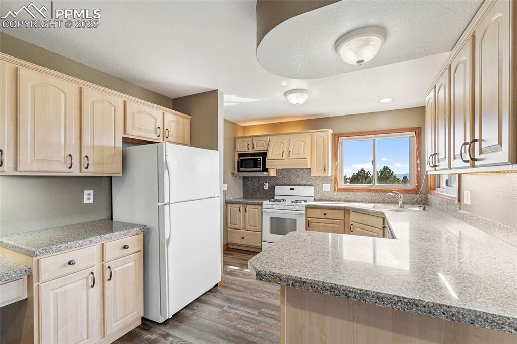 725 Bowstring Road Monument, CO 80132 - Photo 15 of 50 a kitchen with granite countertop white cabinets and white appliances