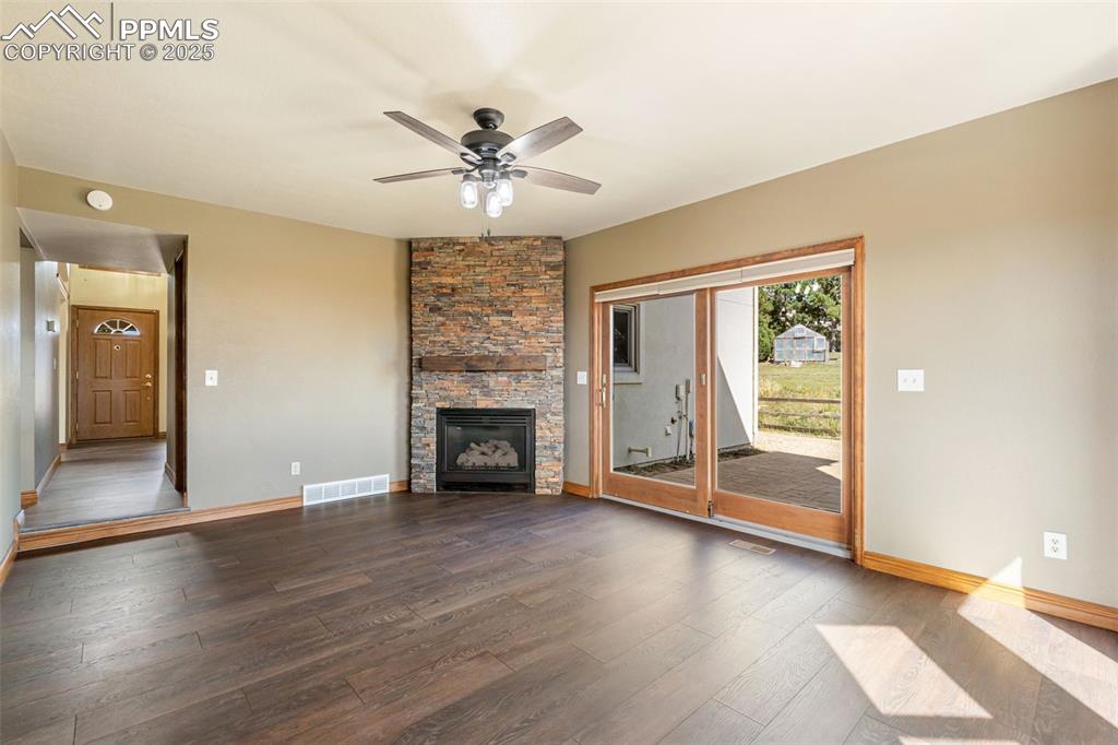 725 Bowstring Road Monument, CO 80132 - Photo 17 of 50 an empty room with wooden floor fireplace and windows