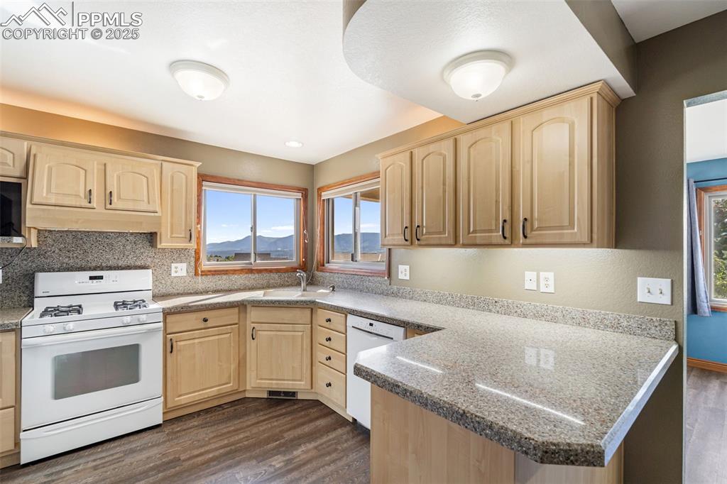 725 Bowstring Road Monument, CO 80132 - Photo 10 of 50 a kitchen with granite countertop a sink stainless steel appliances and white cabinets