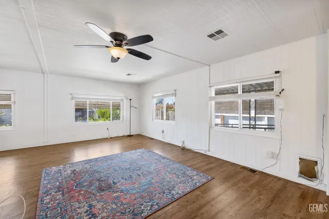 a view of empty room with wooden floor and fan