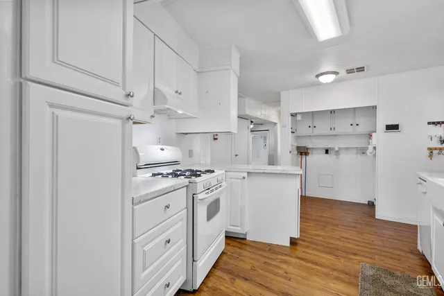 a kitchen with stainless steel appliances white cabinets and wooden floors