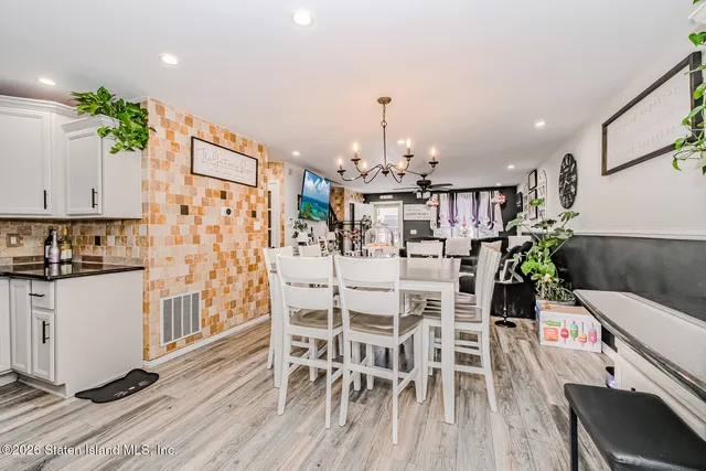 a kitchen with stainless steel appliances kitchen island granite countertop a table chairs and a wooden floor