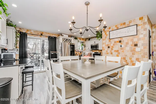 a view of a dining room and livingroom with furniture wooden floor a chandelier