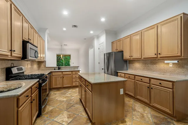 a kitchen with stainless steel appliances granite countertop a stove top oven a sink a refrigerator and white cabinets with wooden floor