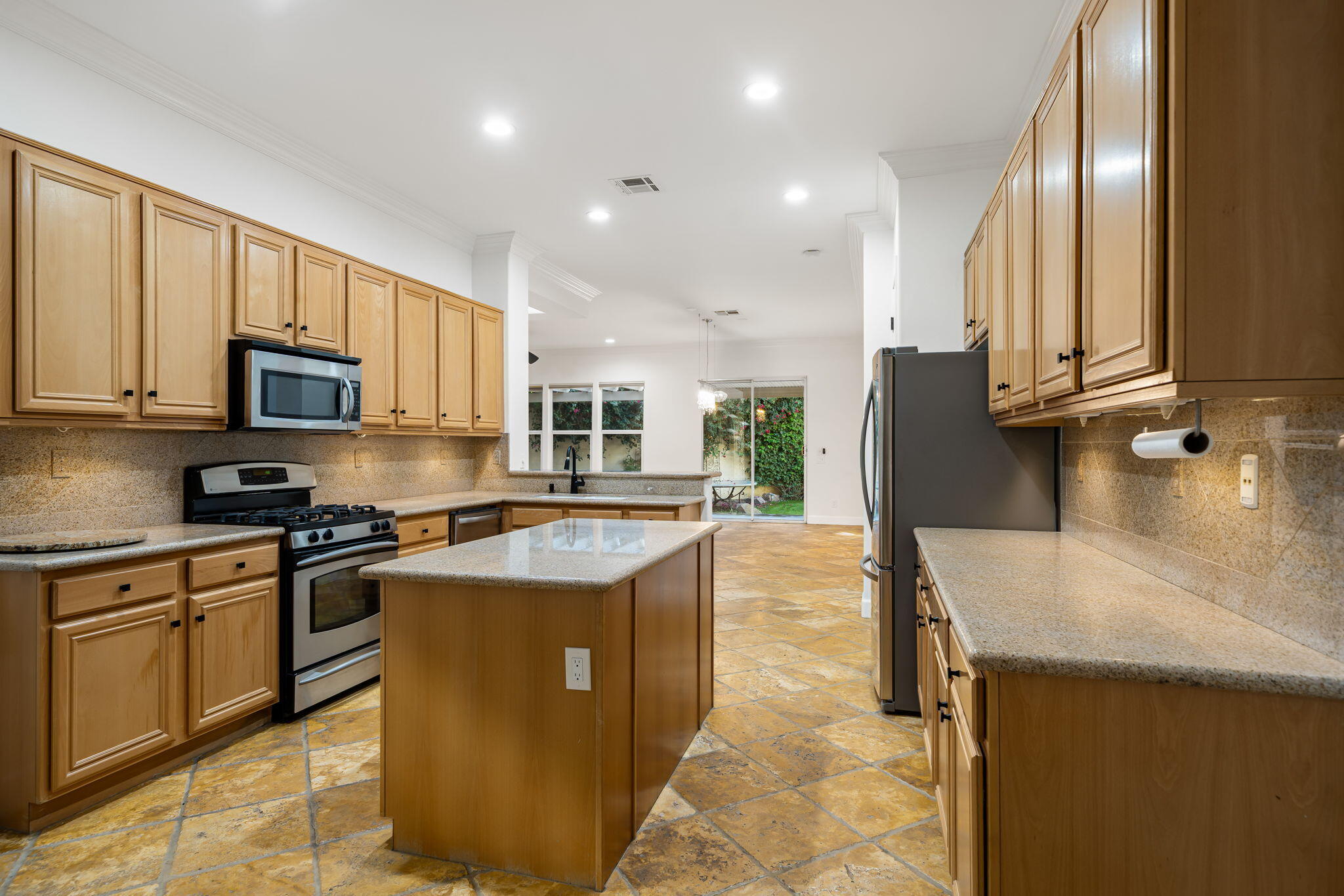 49647 Lewis Road Indio, CA 92201 - Photo 16 of 42 a kitchen with stainless steel appliances granite countertop a stove top oven a sink a refrigerator and white cabinets with wooden floor