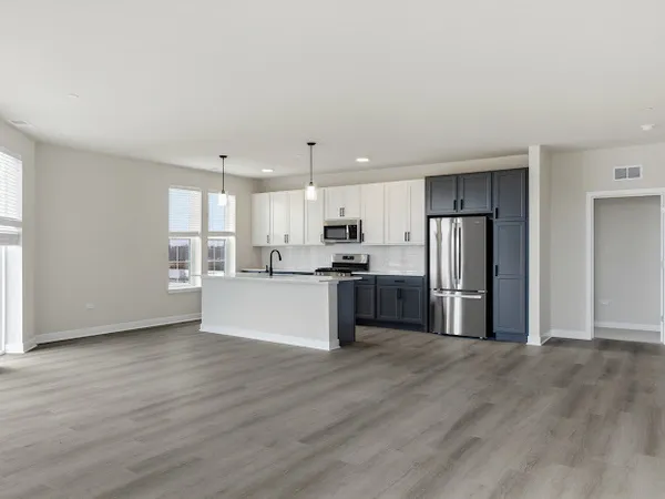 a white kitchen with stainless steel appliances granite countertop a stove a refrigerator a sink and white cabinets with wooden floor