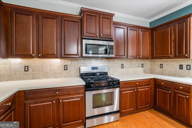 a kitchen with stainless steel appliances a stove top oven a refrigerator a sink dishwasher with a dining table and chairs