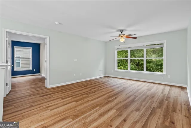 an empty room with wooden floor and windows