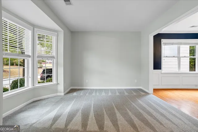 a view of an empty room with window and wooden floor